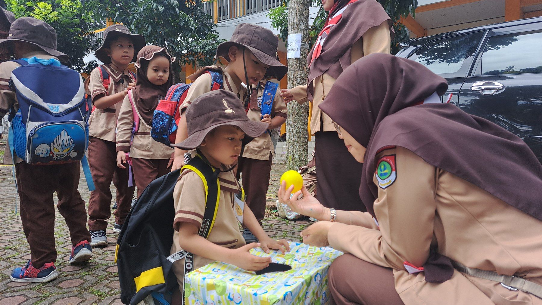 Anak dan pendidik melakukan kegiatan bersama dalam pakaian pramuka.